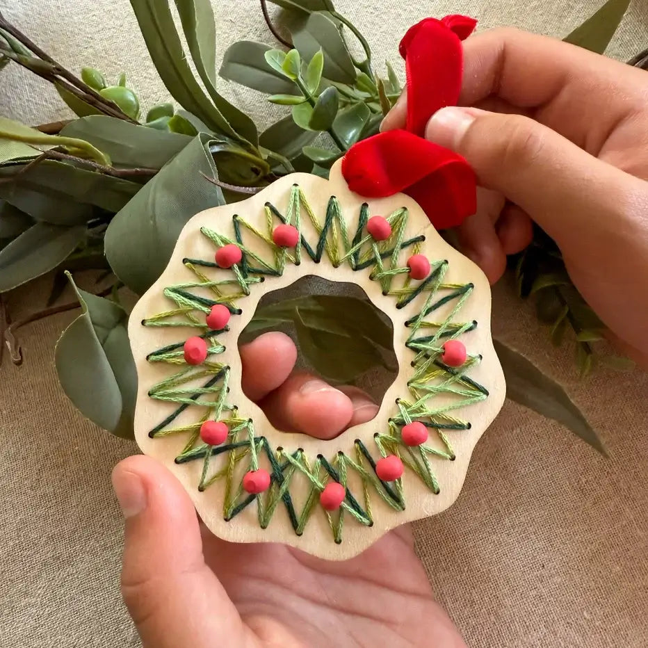 childs hands holding a finished 'stitch your own wreath' Christmas decoration