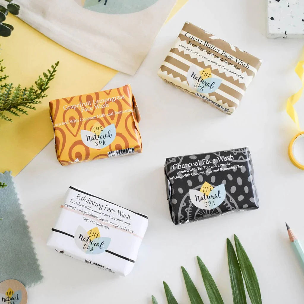 four face wash bars for men wrapped in illustrated paper on a light background