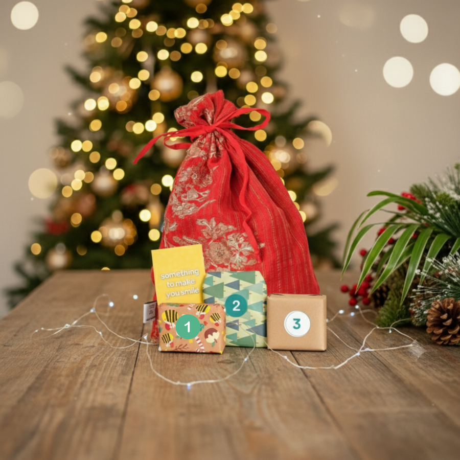 Decorative gift bag with numbered boxes from the 12 days of self care advent calendar on a wooden table in front of a Christmas tree.