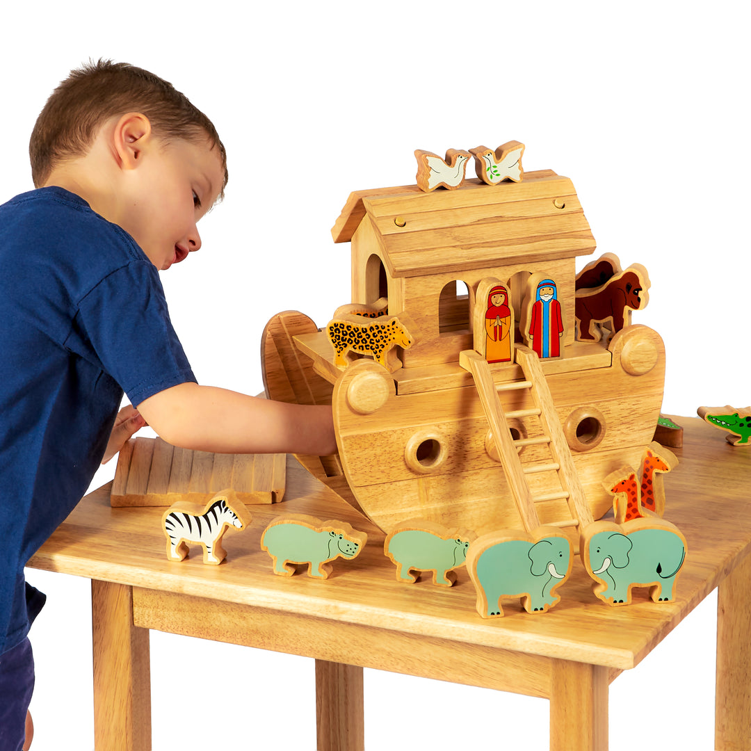 Child playing with a wooden Noah's Ark toy set on a table.
