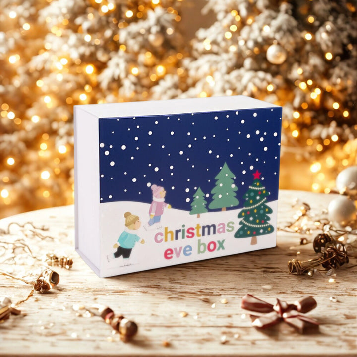 Christmas eve box with festive design on a wooden surface with blurred lights in the background