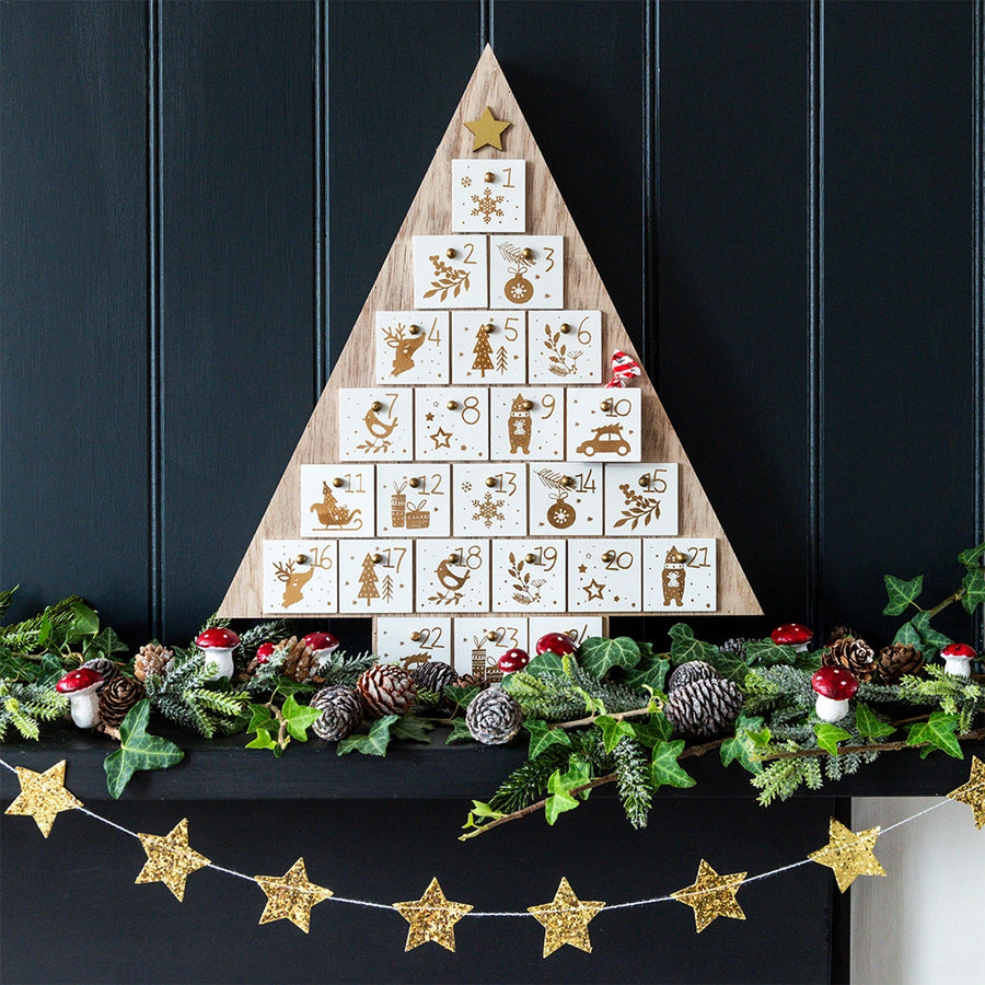 Wooden advent calendar shaped like a Christmas tree on a dark background with decorative elements.