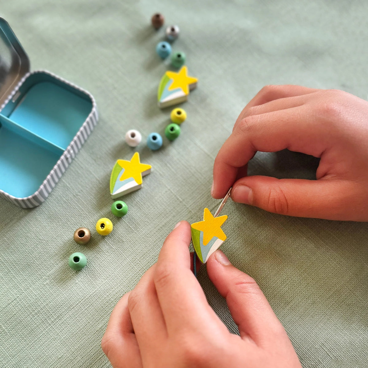 Childs hands threading wooden beads from the Cotton Twist Shooting Star Bracelet kit 