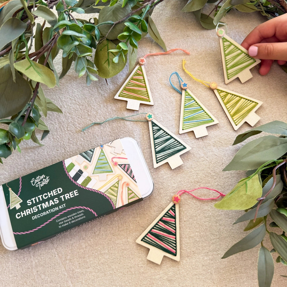 Handmade Christmas tree decorations on a table with a gift tin packaging.