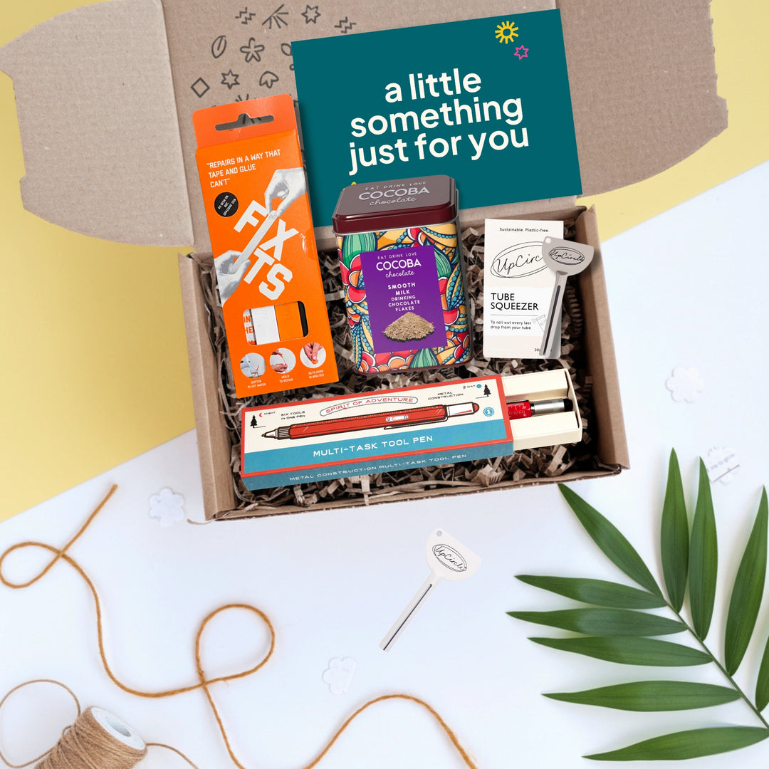 dad's gadgets gift box with fix its, tin of hot chocolate, tube squeezer and a multi tool pen on a light background