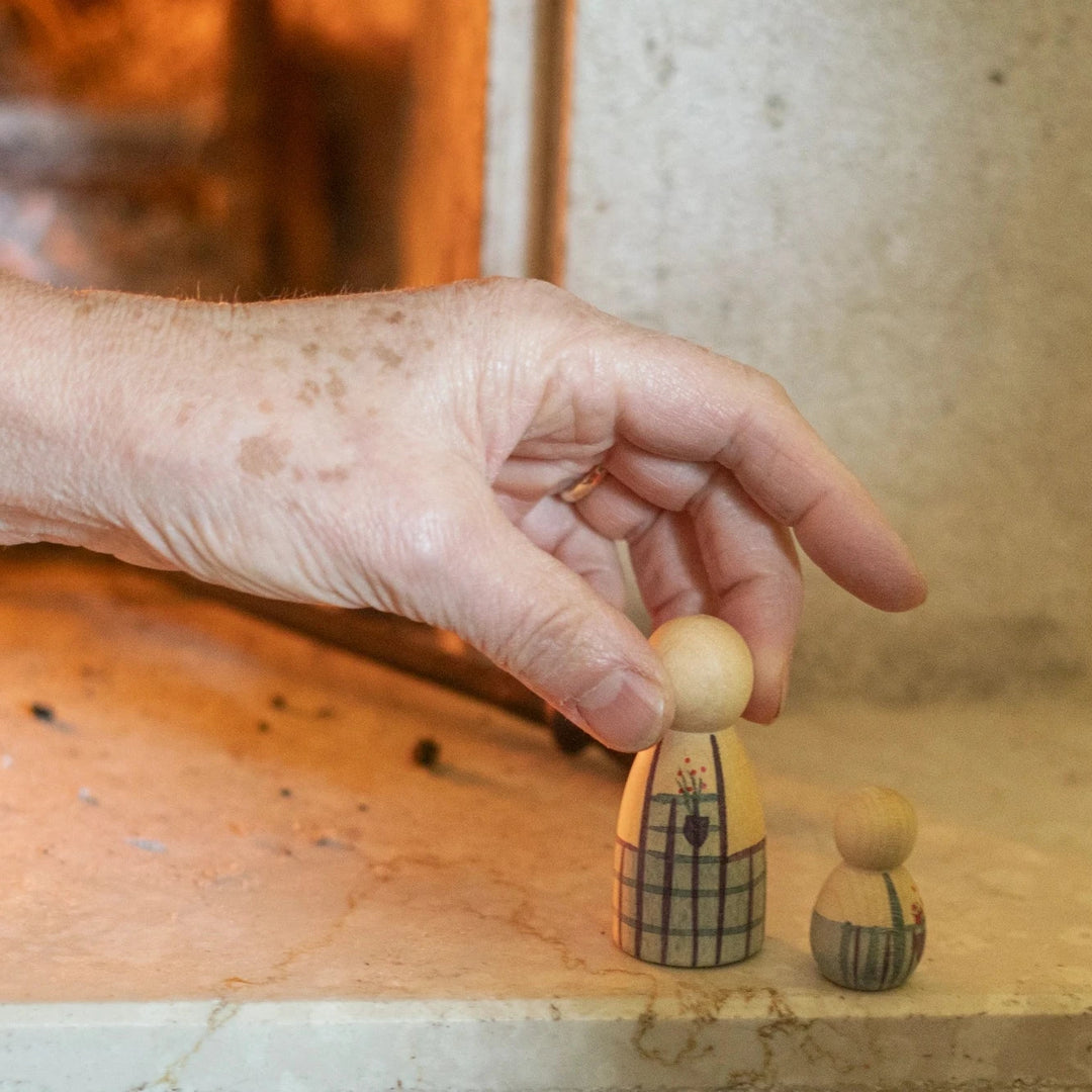 mans hand picking up a painted wooden peg doll from the Grapat Advent calendar