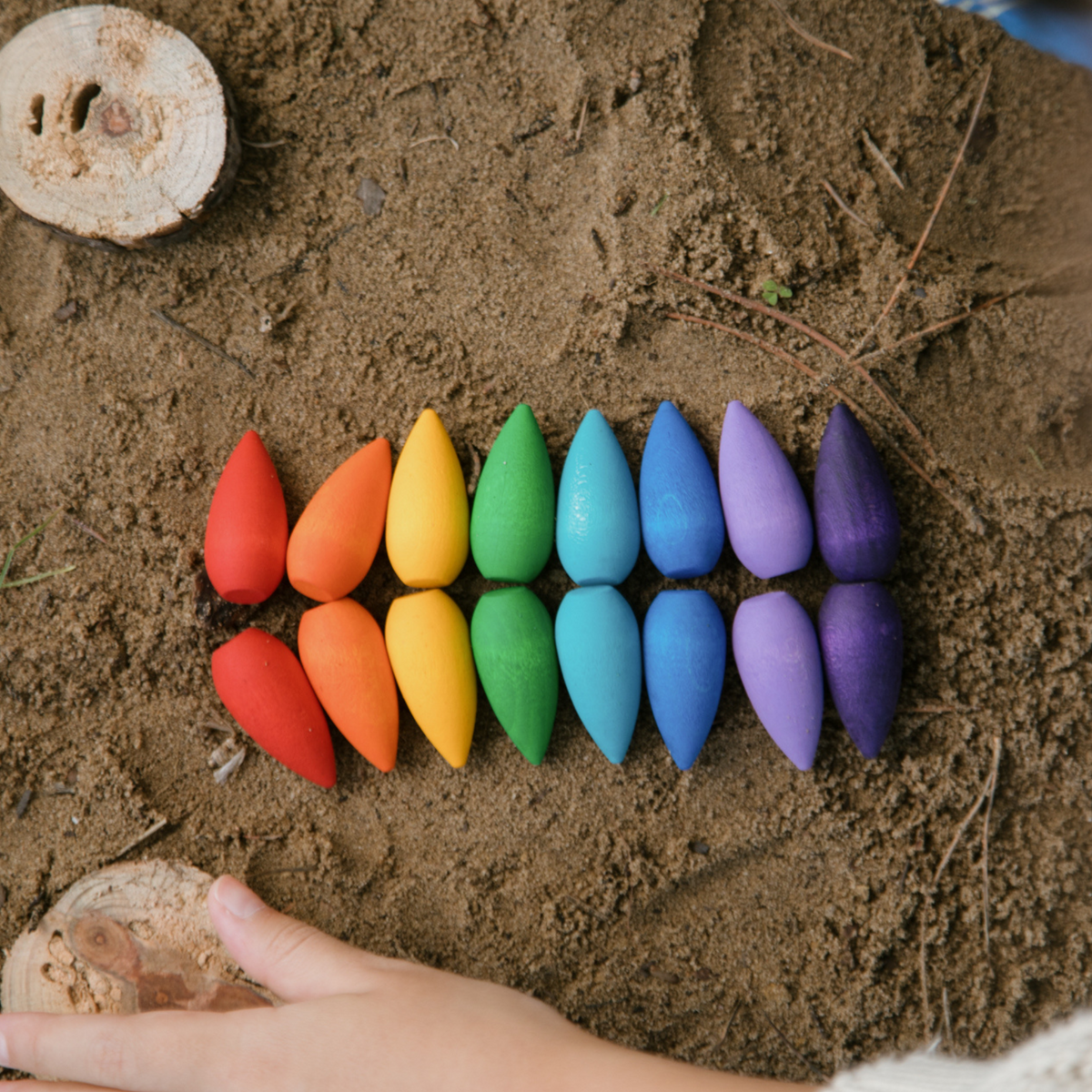 grapat rainbow wooden snowflakes on a mud background with a childs hands playing