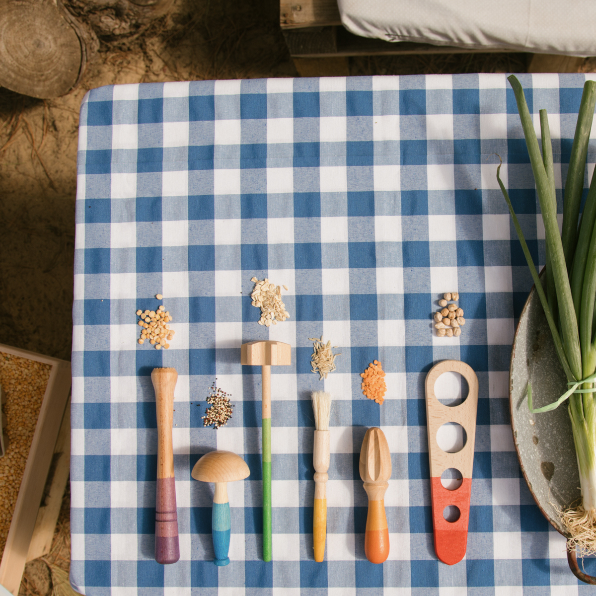 six wooden tools for pretend play on a blue checked cloth 