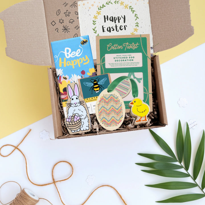 Box of Easter-themed toys and crafts for children on a white background with a Happy Easter card