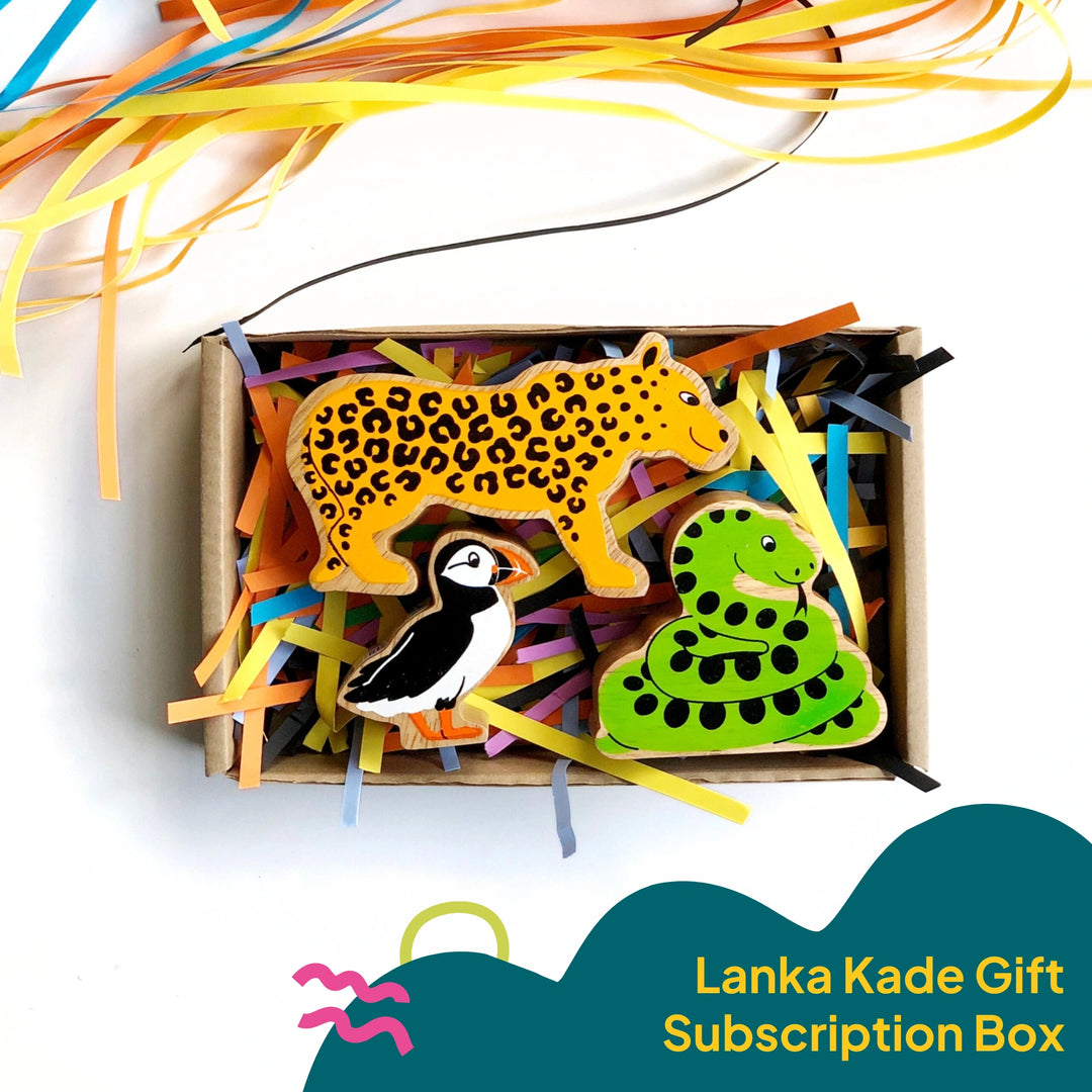 Lanka Kade Play Figures Gift Subscription box. The box pictured is filled with colourful shredded paper and has a wooden leopard, snake and puffin inside. The figures are suitable for children 10 months and over 