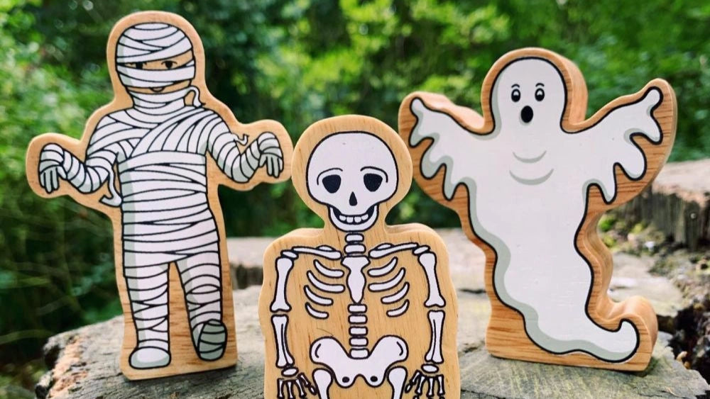wooden mummy, ghost and skeleton play figures outdoors on a wooden log. Halloween themed play figures made by lanka kade for children over 10 months