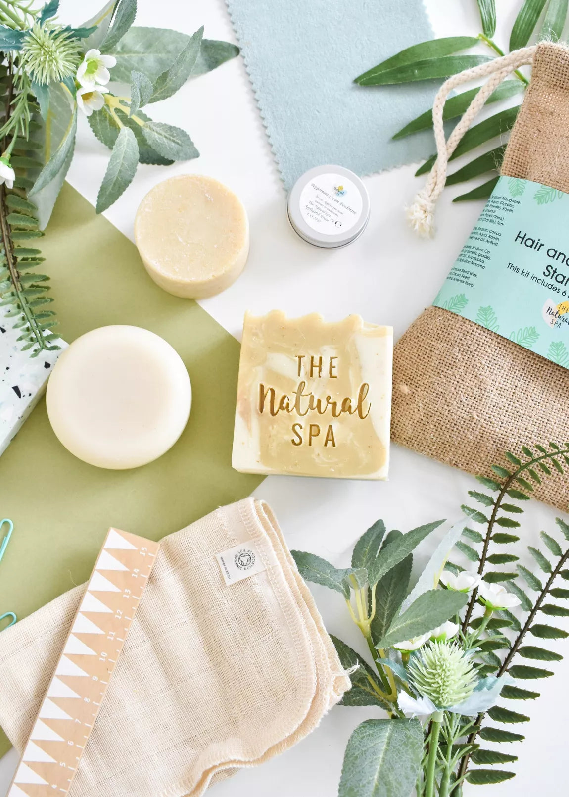 overhead view of products from the  Natural Spa Fresh Hair and Body Starter Kit with eucalyptus and mint shampoo bar, conditioner bar, soap and deodorant, a wash cloth and travel bag. 