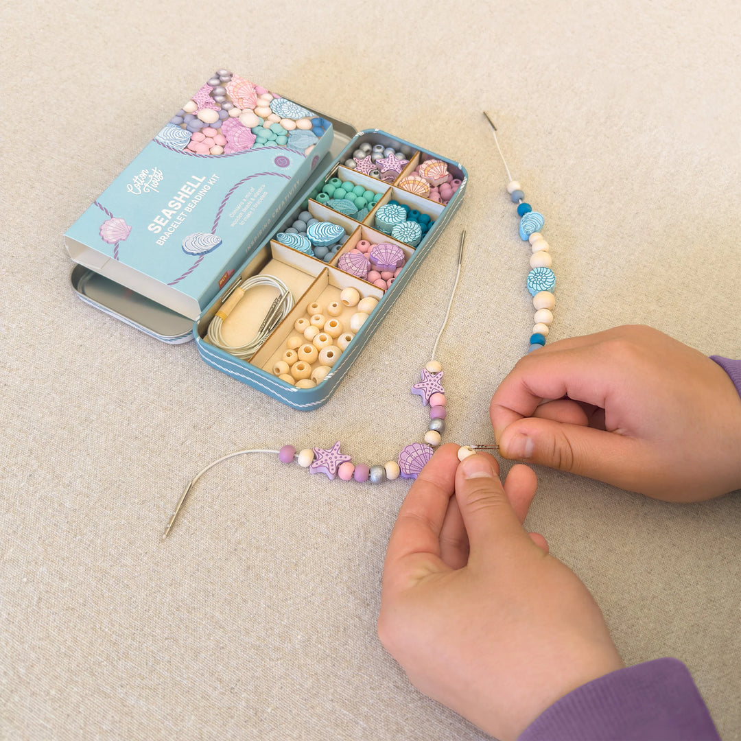 childs hands using seashell beading kit to make a bracelet