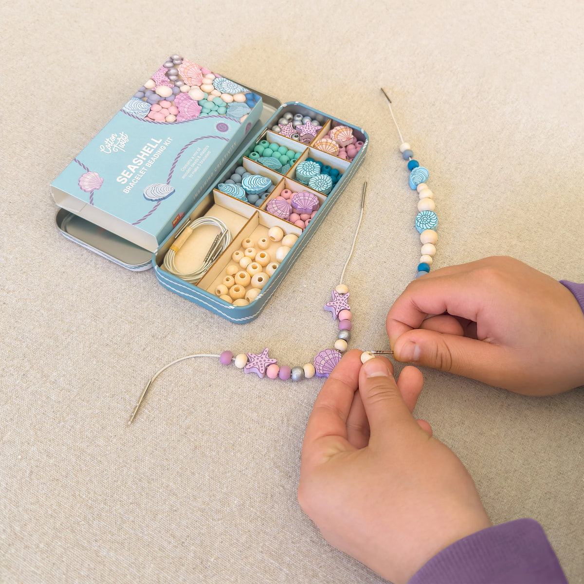 childs hands using seashell beading kit to make a bracelet