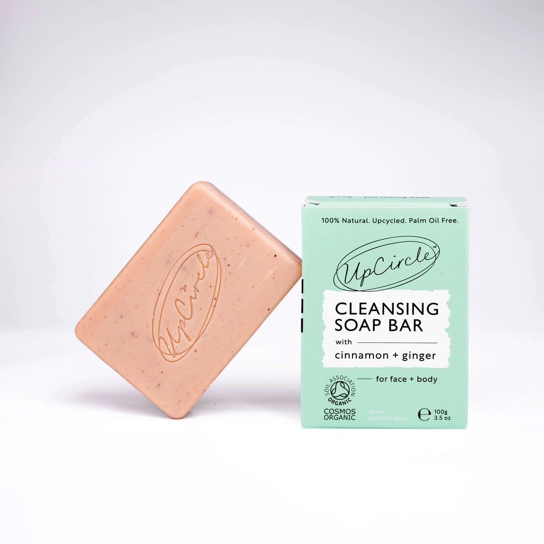 UpCircle Cleansing Soap Bar with Cinnamon + Ginger. The bar is peach coloured and is stamped with the upcircle logo in swirly writing