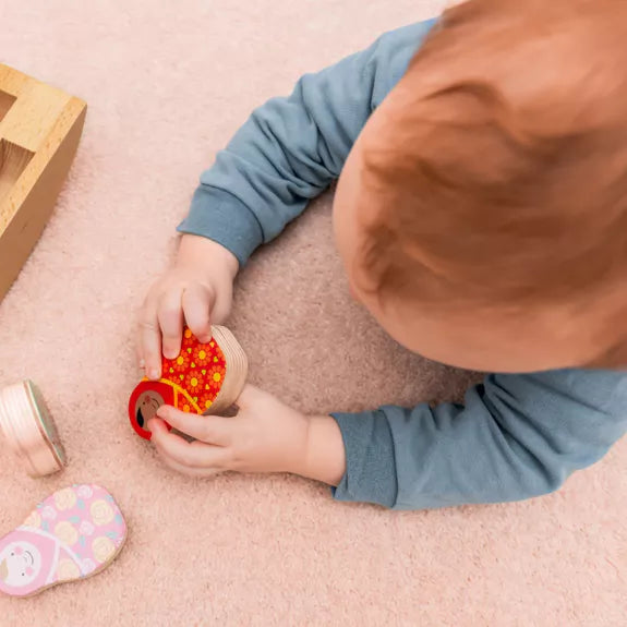 baby playing with Rosa + Bo Collectible Wooden play figures with russian doll designs in pink blue and red. 