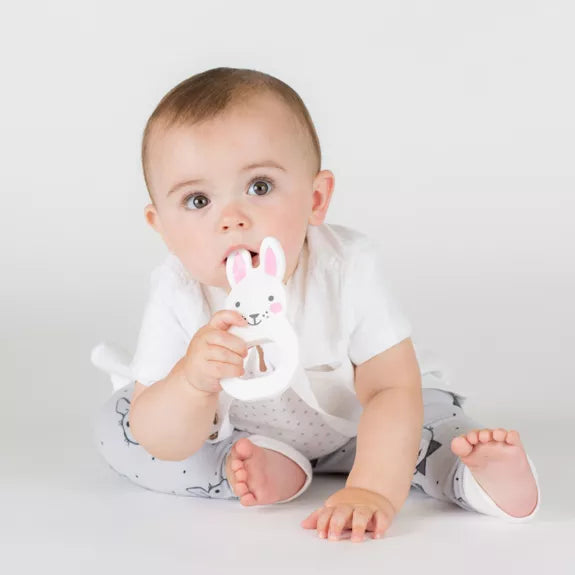 baby with a white bunny shaped silicone teething toy with pink ears 