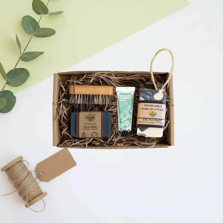 Set of mens natural skincare products in a beard and skincare box with a green leafy branch on a light background