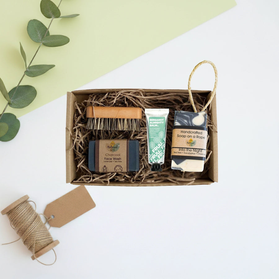 Set of mens natural skincare products in a beard and skincare box with a green leafy branch on a light background