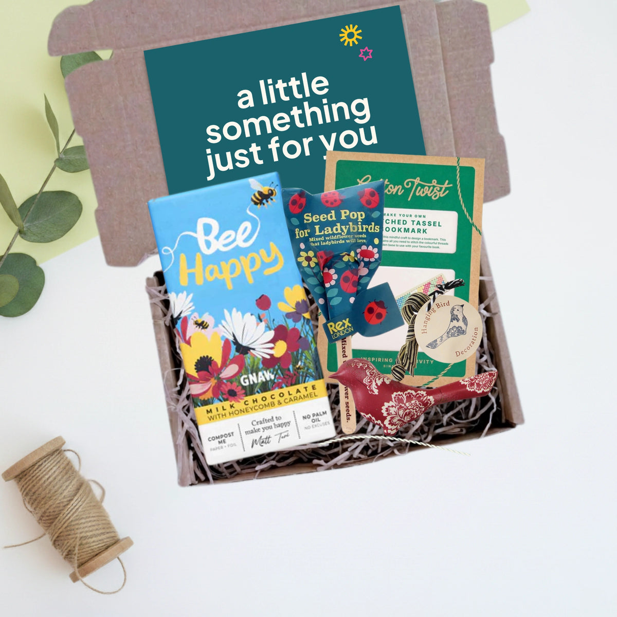 Gift box with 'Bee Happy' chocolate, seed pop, and other items on a white background