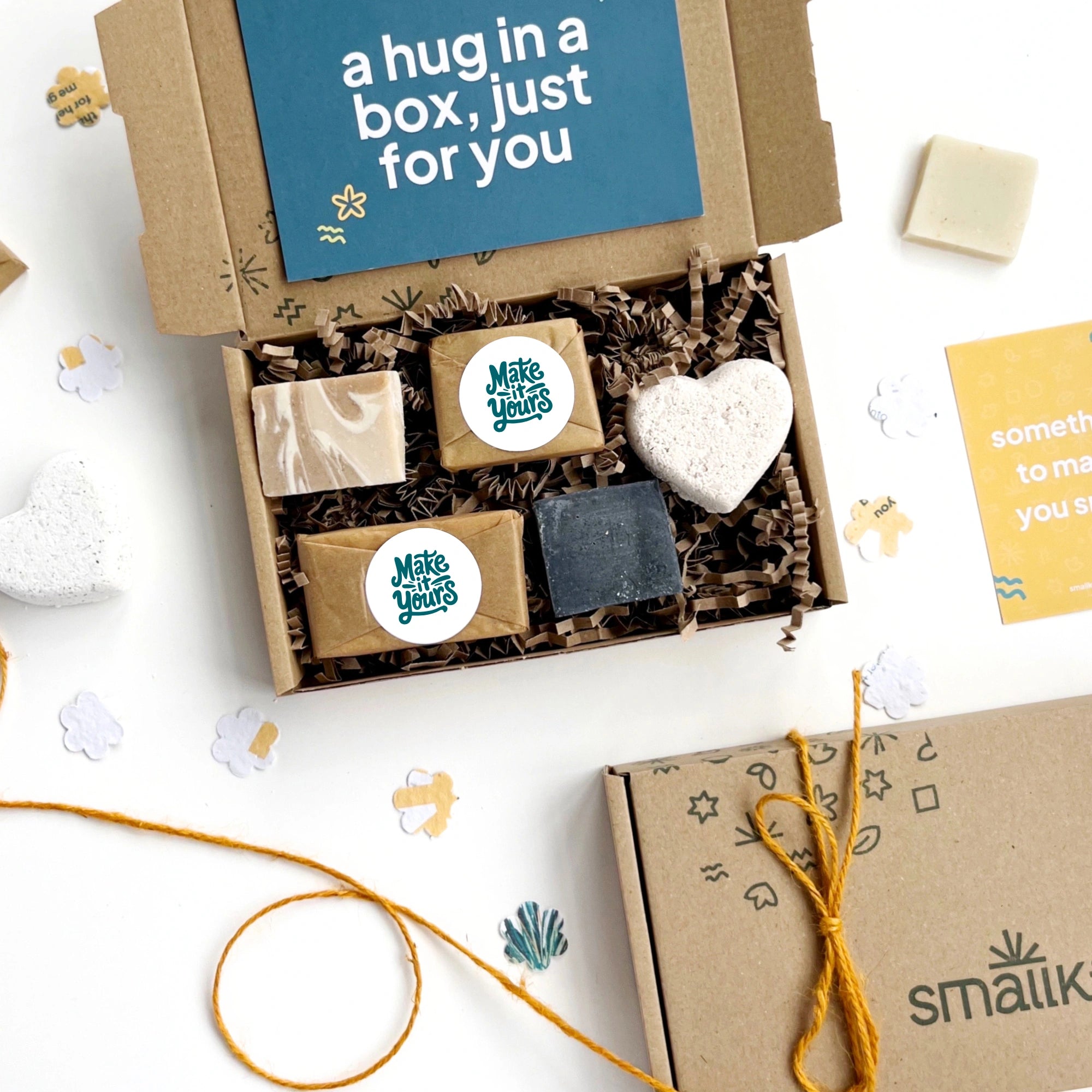Gift box with soaps and a heart-shaped bath bomb and small soap bars featuring 'Make It Yours' slogan, on a white background.
