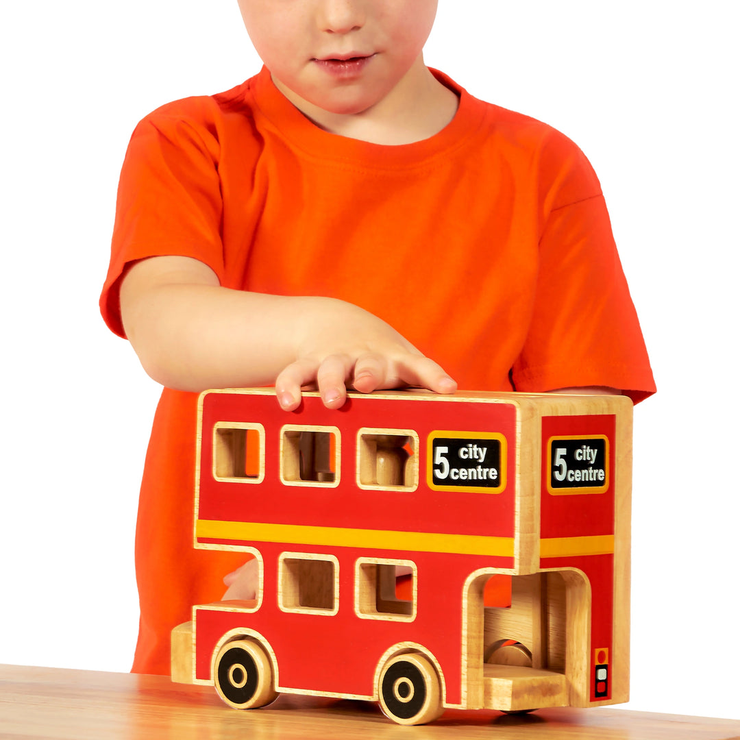 boy playing with a red London bus toy with wooden people inside