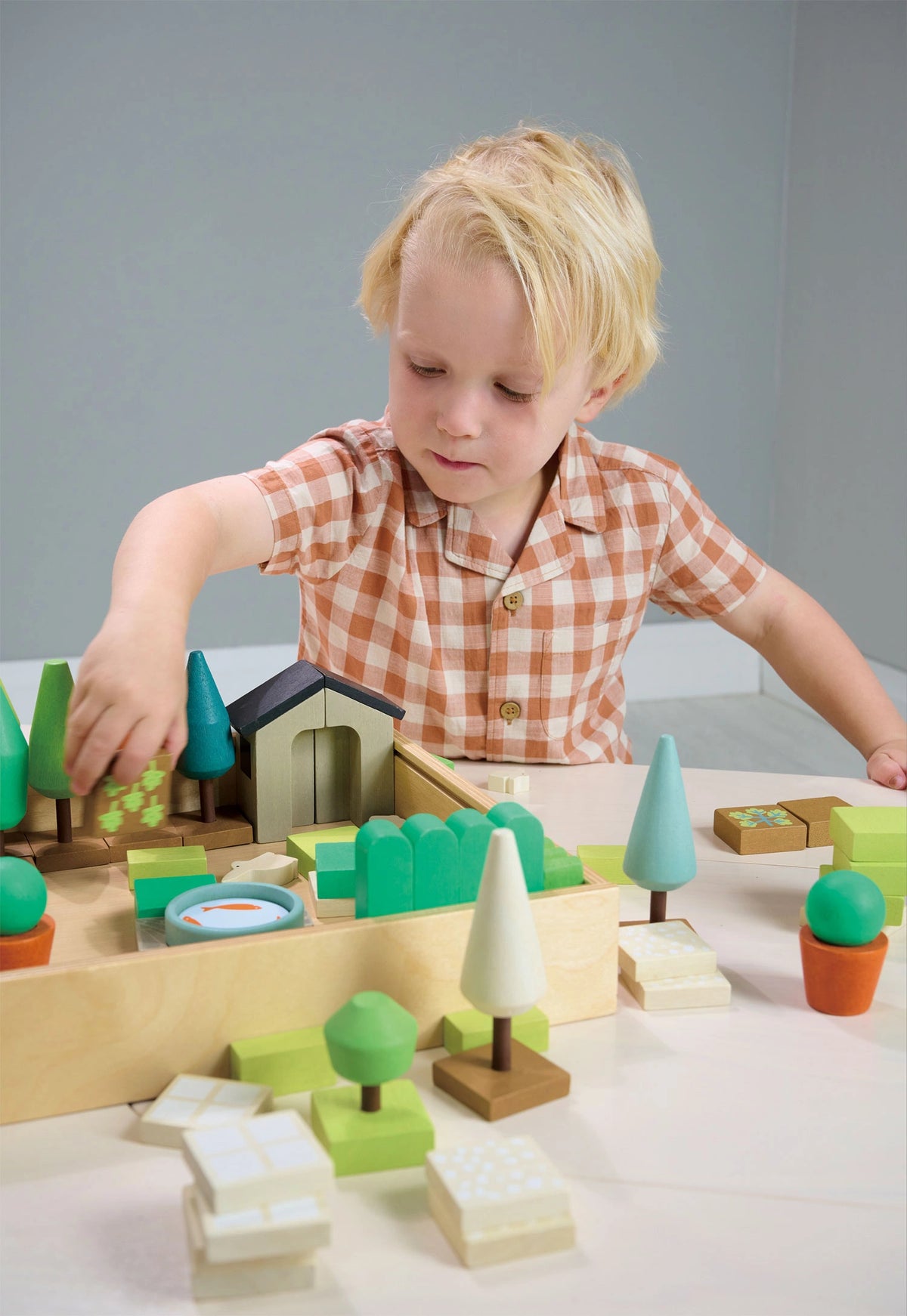 boy playing with Tender Leaf Little Garden Designer wooden play set for nature themed open ended play. Comes in wooden storage box. For age 3+