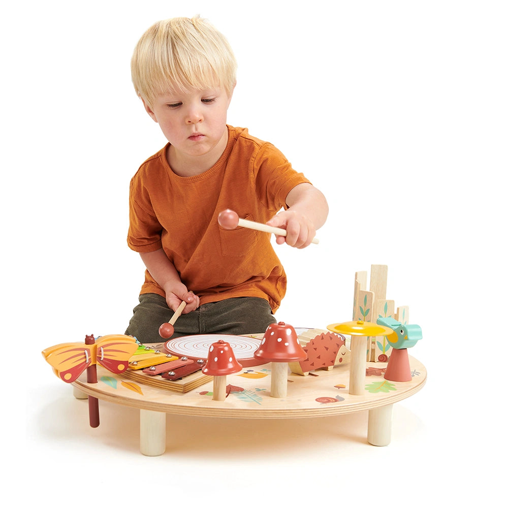 boy playing with Tender Leaf Musical Table with forest creatures, bells, drum, xylophone and chime bars instruments. For age 3+