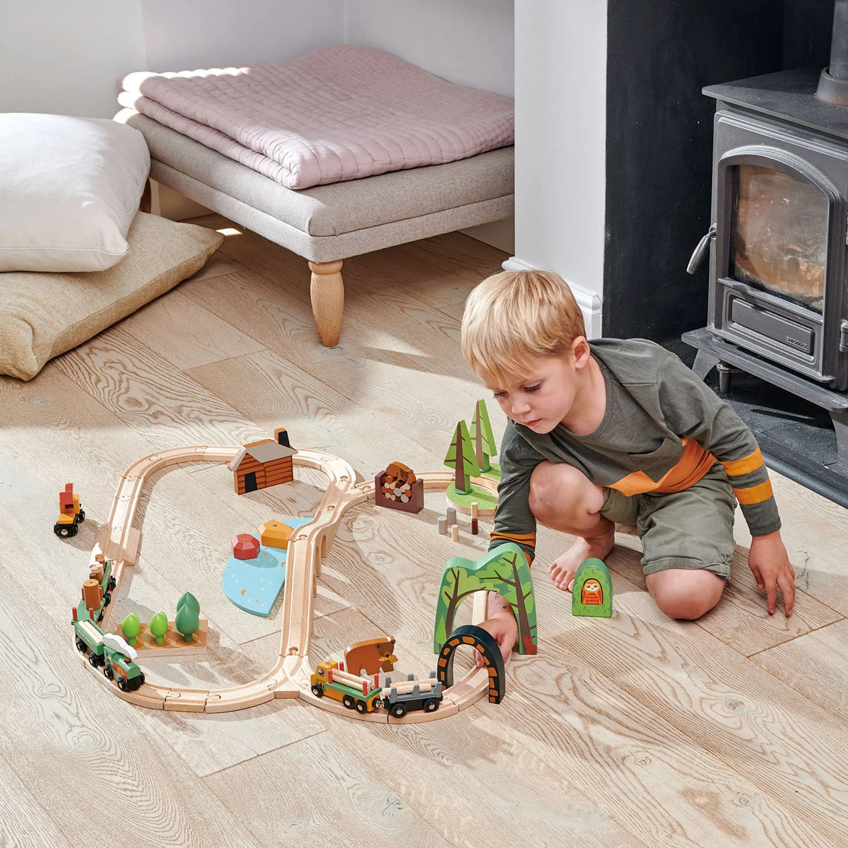 boy playing with Tender Leaf Wild Pines Train Set. design-led 30-piece wooden toy train set and accessories including trees, vehicles and buildings. For kids age 3+