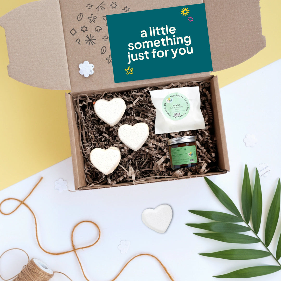Gift box with heart-shaped bath bombs, wax melts and a candle on a white background