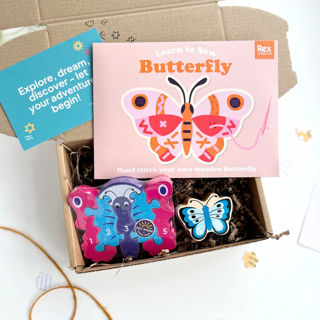 Butterfly-themed children's gift box with  craft kit, colourful butterfly puzzle and a blue butterfly play figure in an open card gift box.