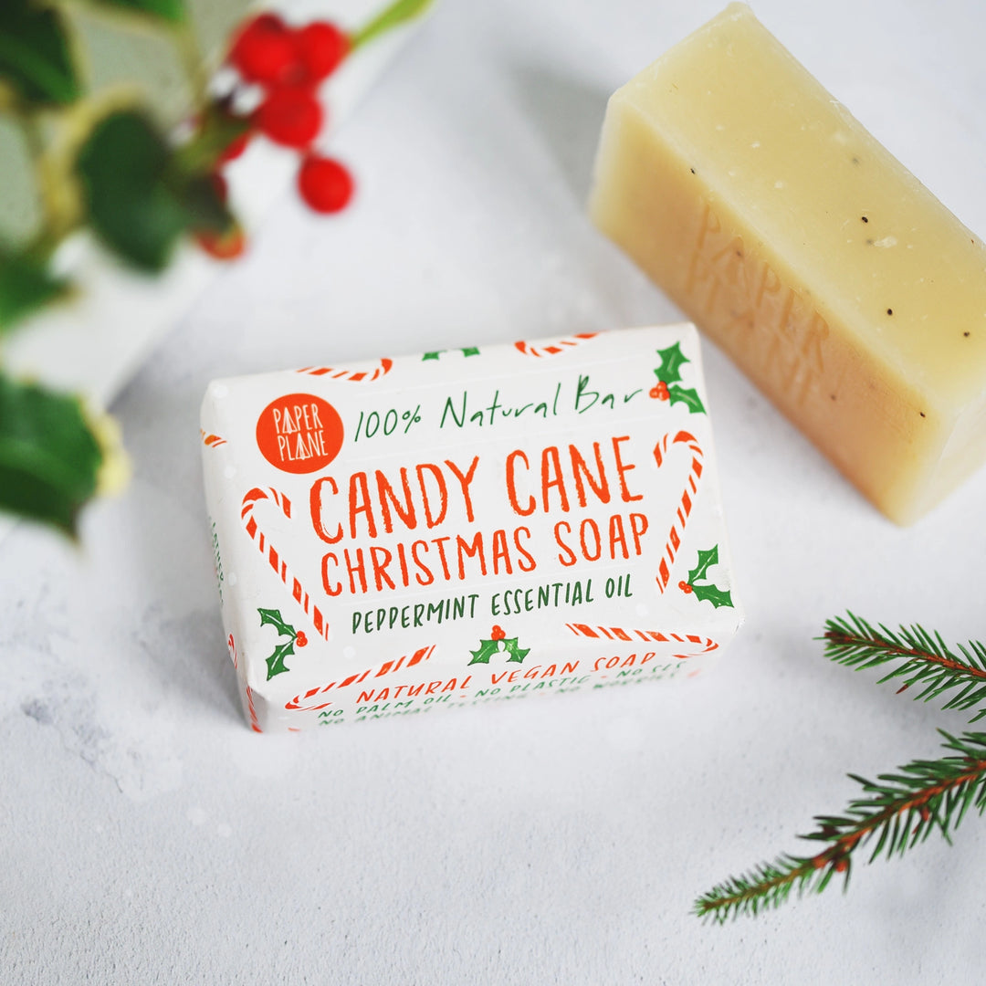 Candy Cane Christmas soap bar with packaging on a white surface with greenery.