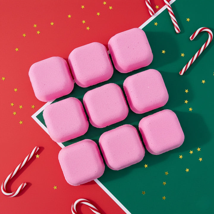 nine pink square candy cane shower steamers with a red and green festive background