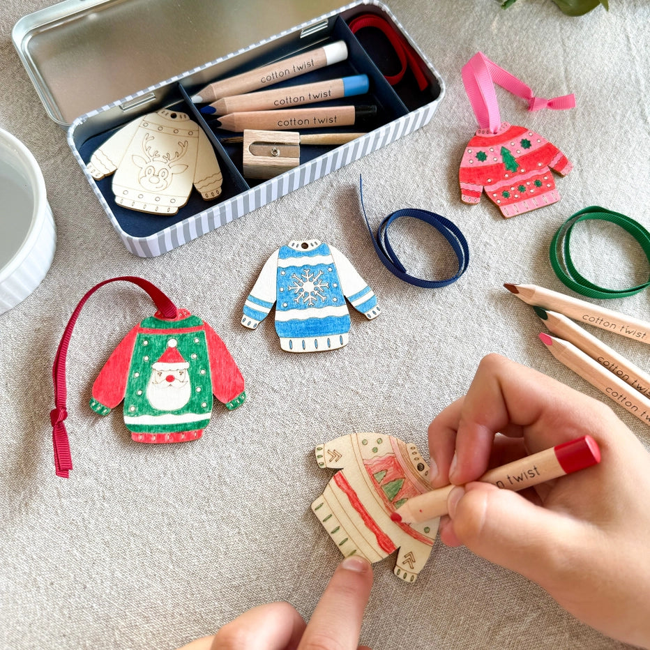 child's hand colouring in a wooden jumper decoration from the Cotton Twist craft kit. For kids age 3+