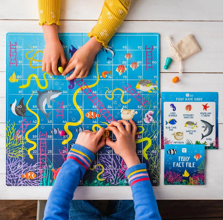 Children playing with an educational fishy snakes and ladders game on a wooden table.
