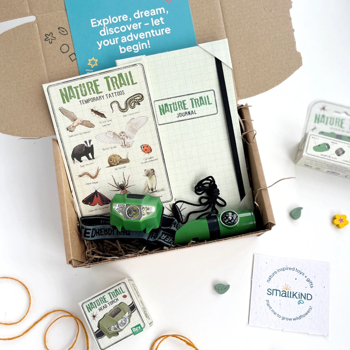 Kids nature themed gift box including a nature trail journal, animal temporary tattoos, a head torch, nature whistle and some stickers. The products are inside a hand stamped gift box with a gift card that reads 'explore, dream, discover - let your adventure begin'.