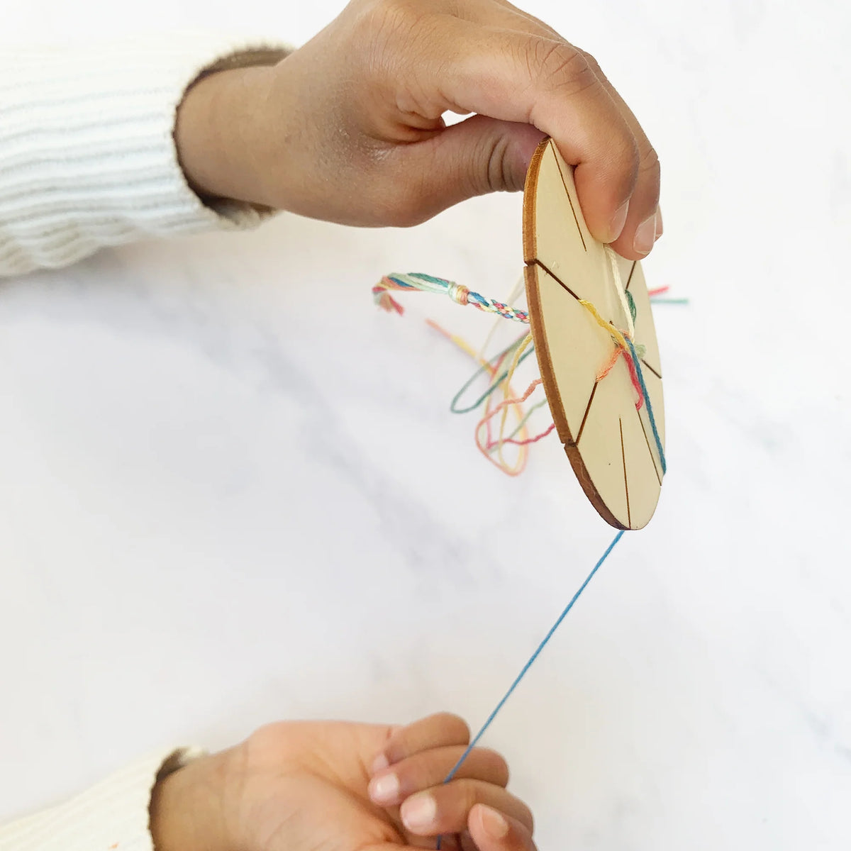 child using the cotton twist bracelet making wooden tool