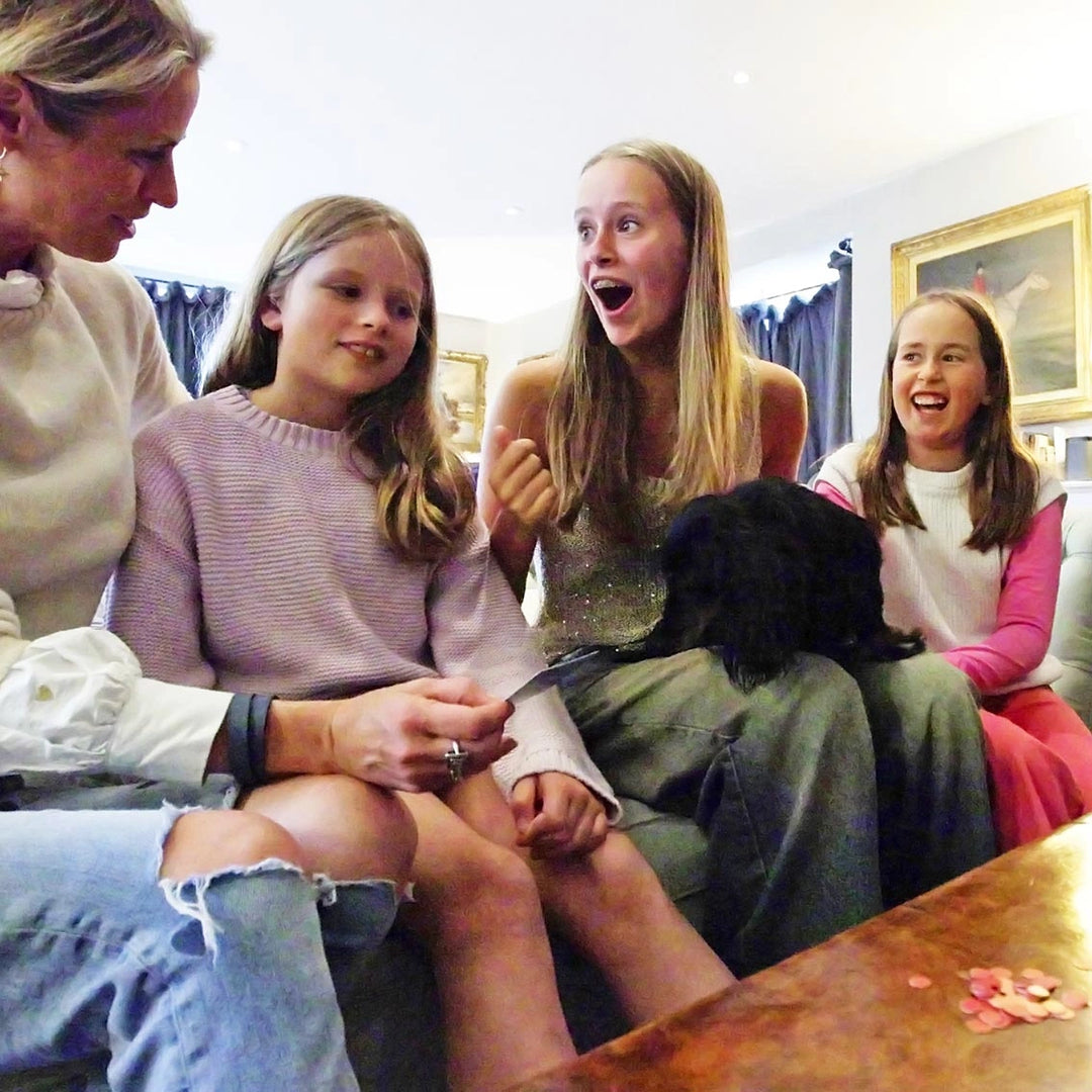 Four people sitting together, two of whom are children, with a dog on a couch.