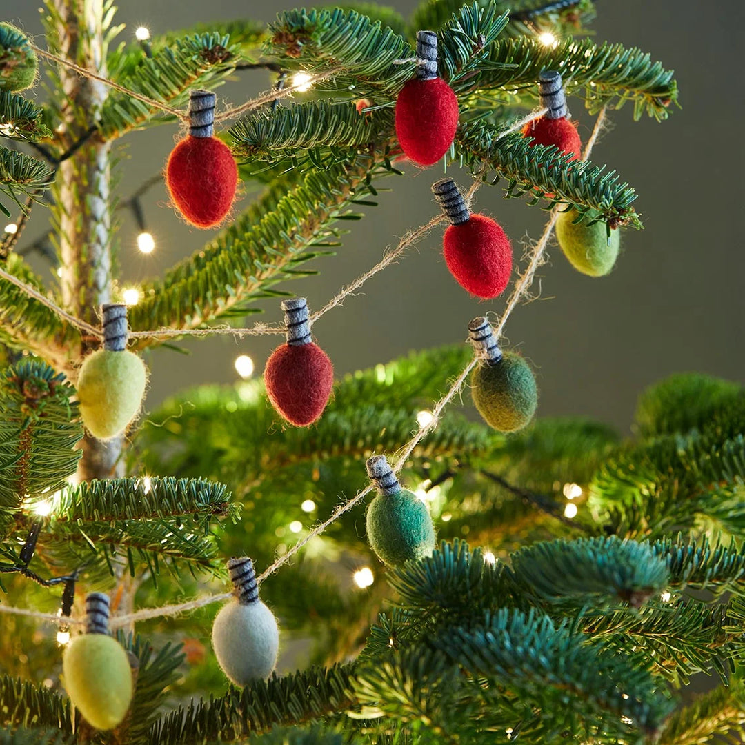 Decorative string lights with red, green, and white bulbs on a Christmas tree.