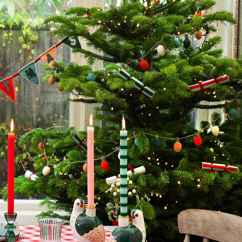 Decorated Christmas tree with candles and festive decorations including Christmas felt lightbulb garland in a home setting.