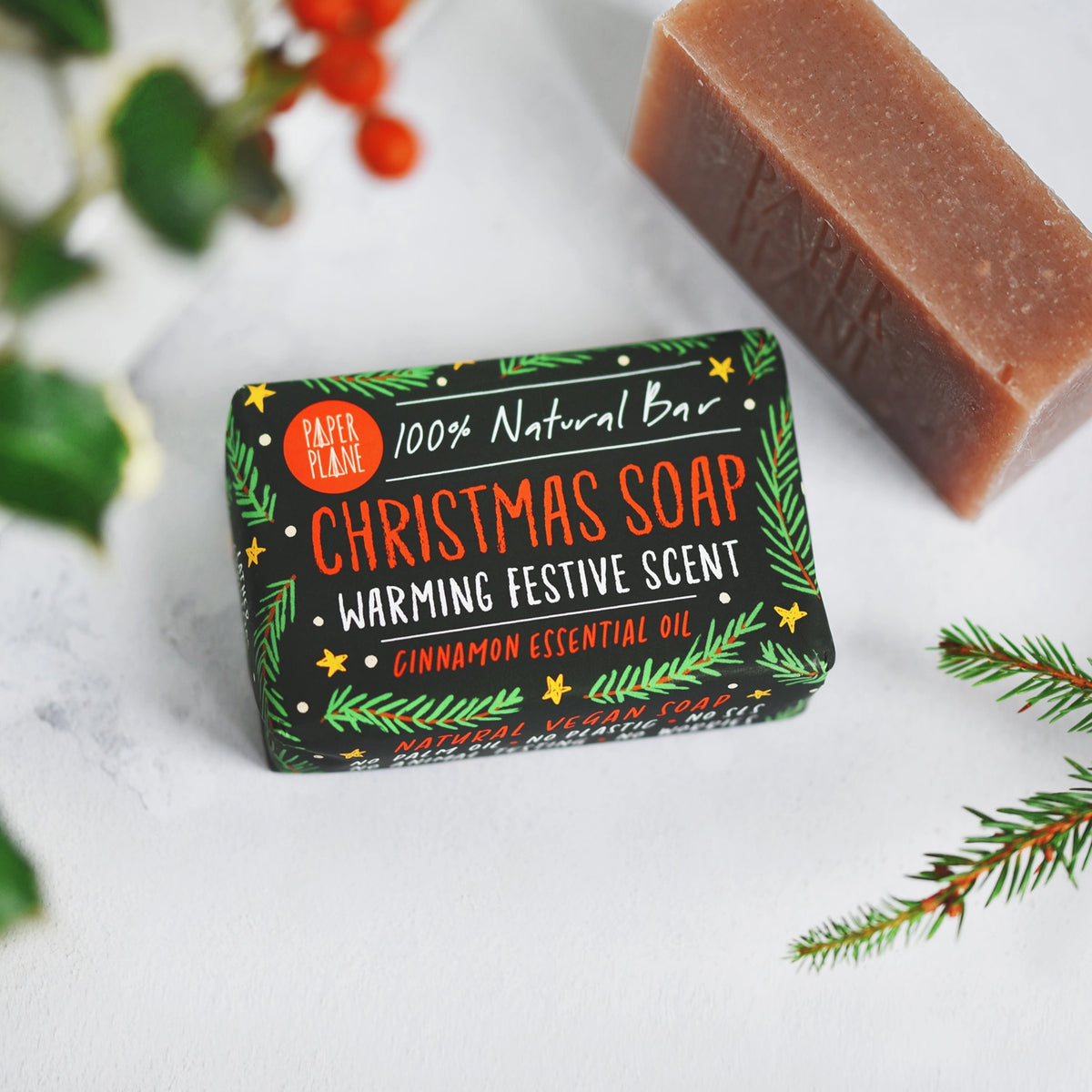 Christmas soap bar in festive packaging on a white background with holly branches