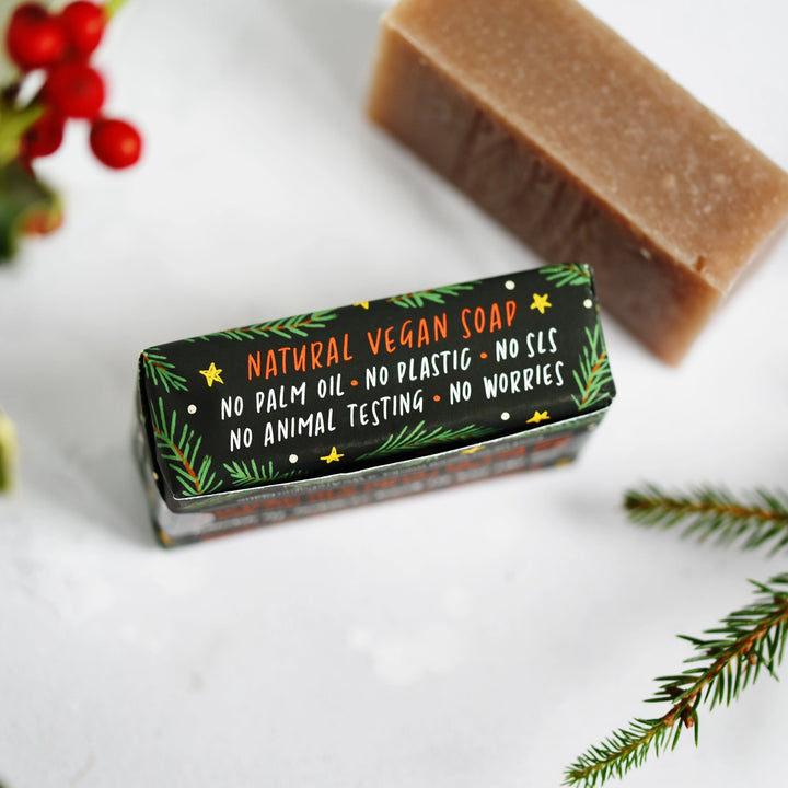 Bar of soap with a black label on a white background with greenery.