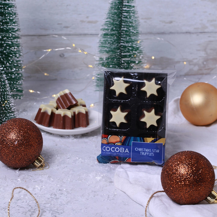 Cocoba Christmas star truffles packaging with festive decorations on a wooden surface.