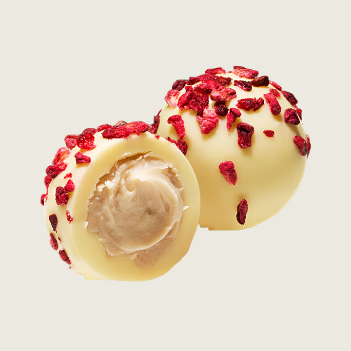 two White chocolate raspberry and marc de champagne truffles truffles with pink toppings on a white background