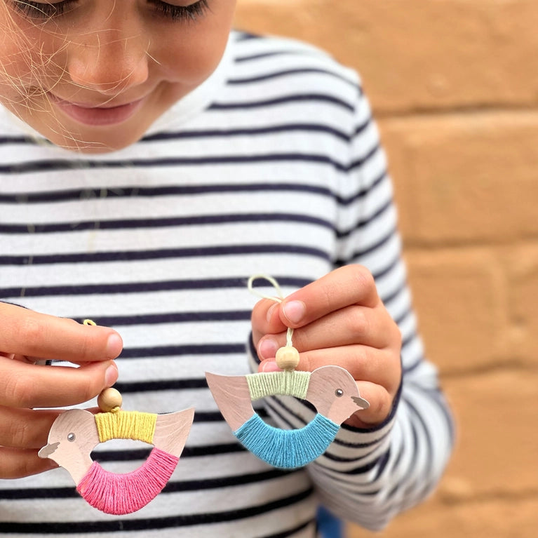 girl holding two finished bird decorations from the make your own birds kit by cotton twist.