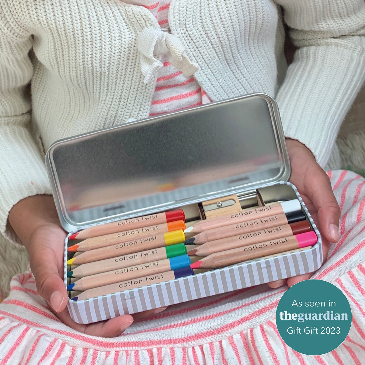 Girls hands holding an open tin of Cotton Twist Jumbo Water Colour Pencils in a Tin
