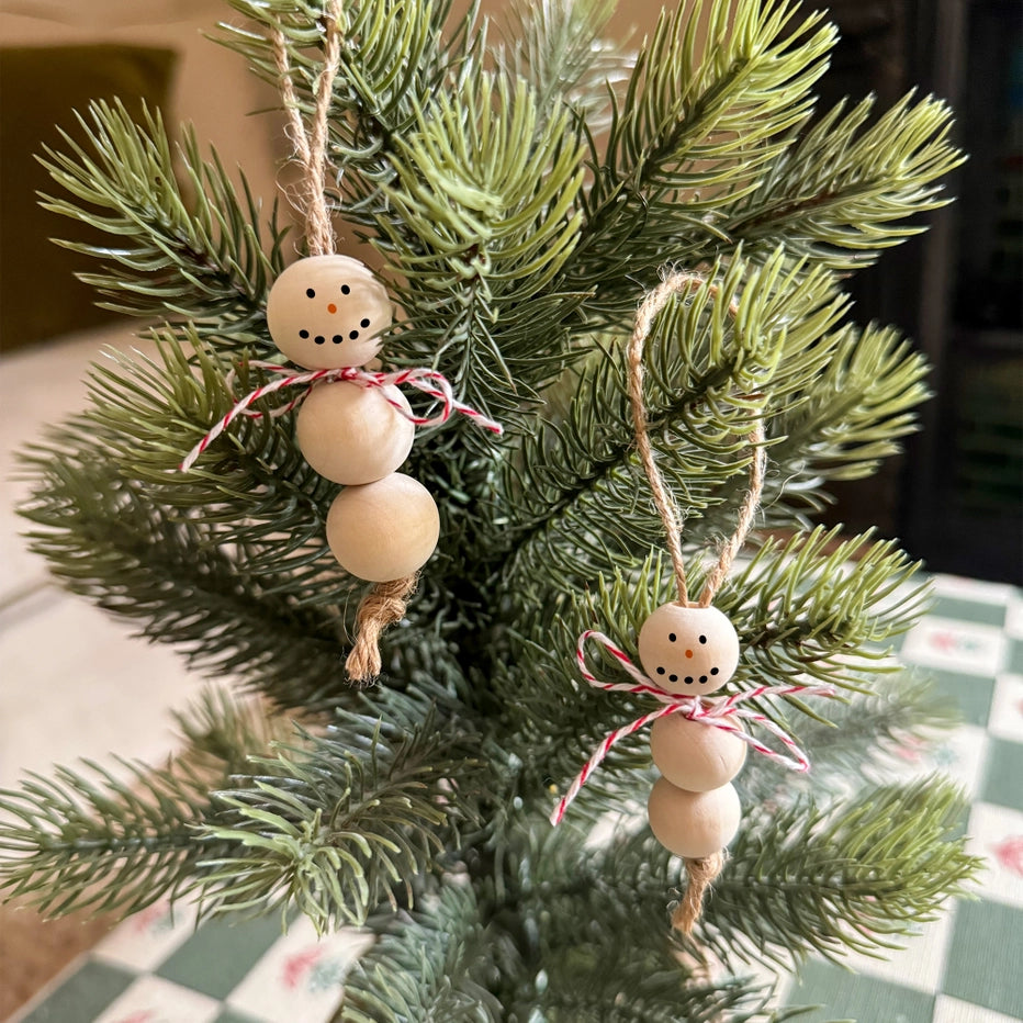 Wooden snowman ornaments hanging on a Christmas tree