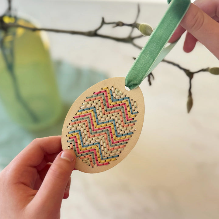 childs hand holding a make your own stitched egg decoration by Cotton Twist