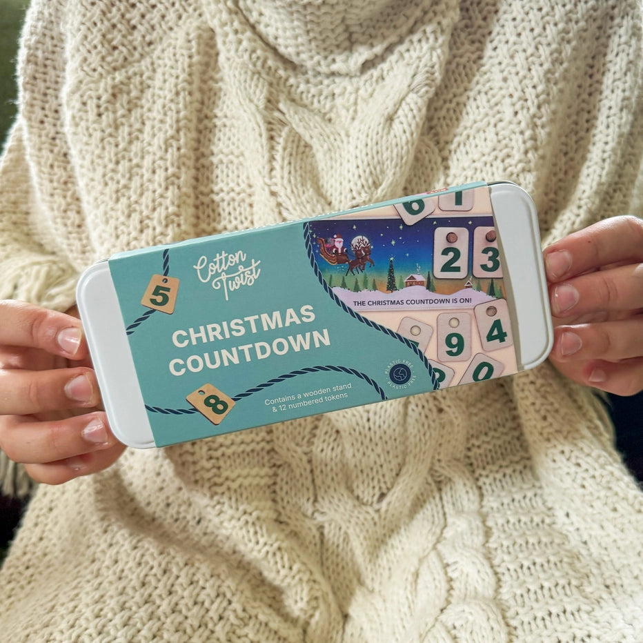 child's hands holding a cotton twist Christmas Countdown calendar in a tin