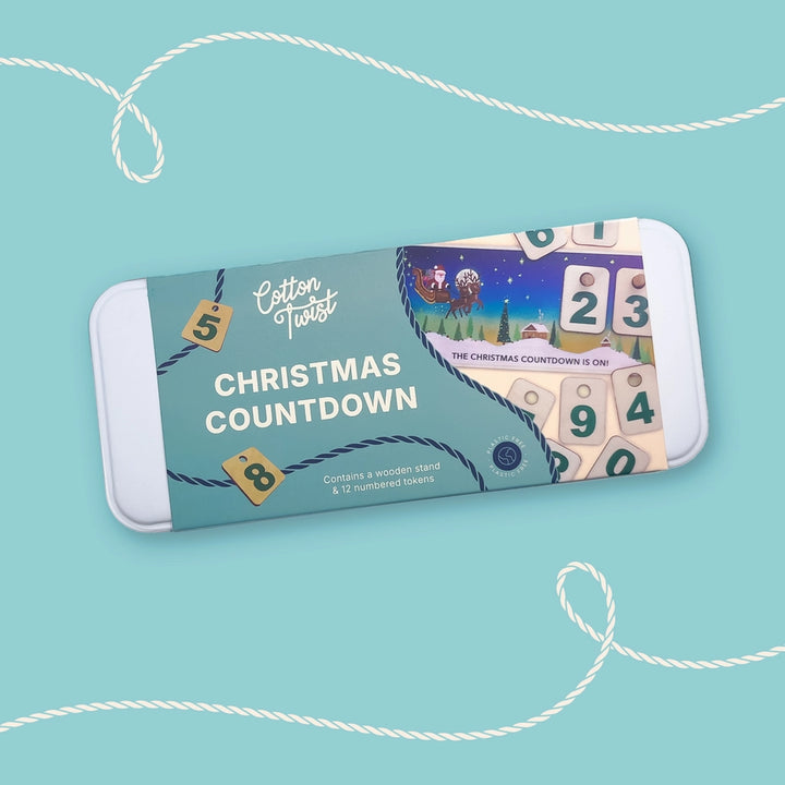Cotton Twist Christmas Countdown Calendar in a tin with illustrated paper ban on a blue background. For age 3+